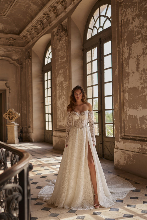 Lace wedding dress with slit, corset, and long sleeves on stairs