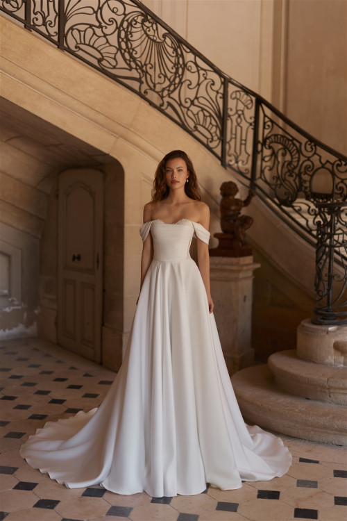 Smooth wedding dress with drooping straps and long train on stairs